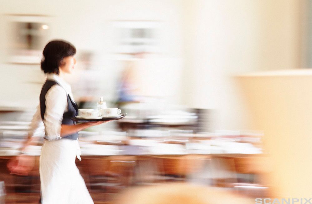 Travel kvinnelig servitør på kafé bærer et brett med kopper. Foto.