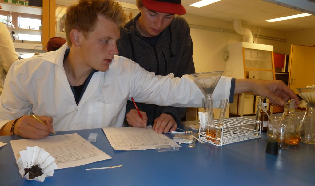 To gutter analyserer jordprøver på laboratorium. Foto.