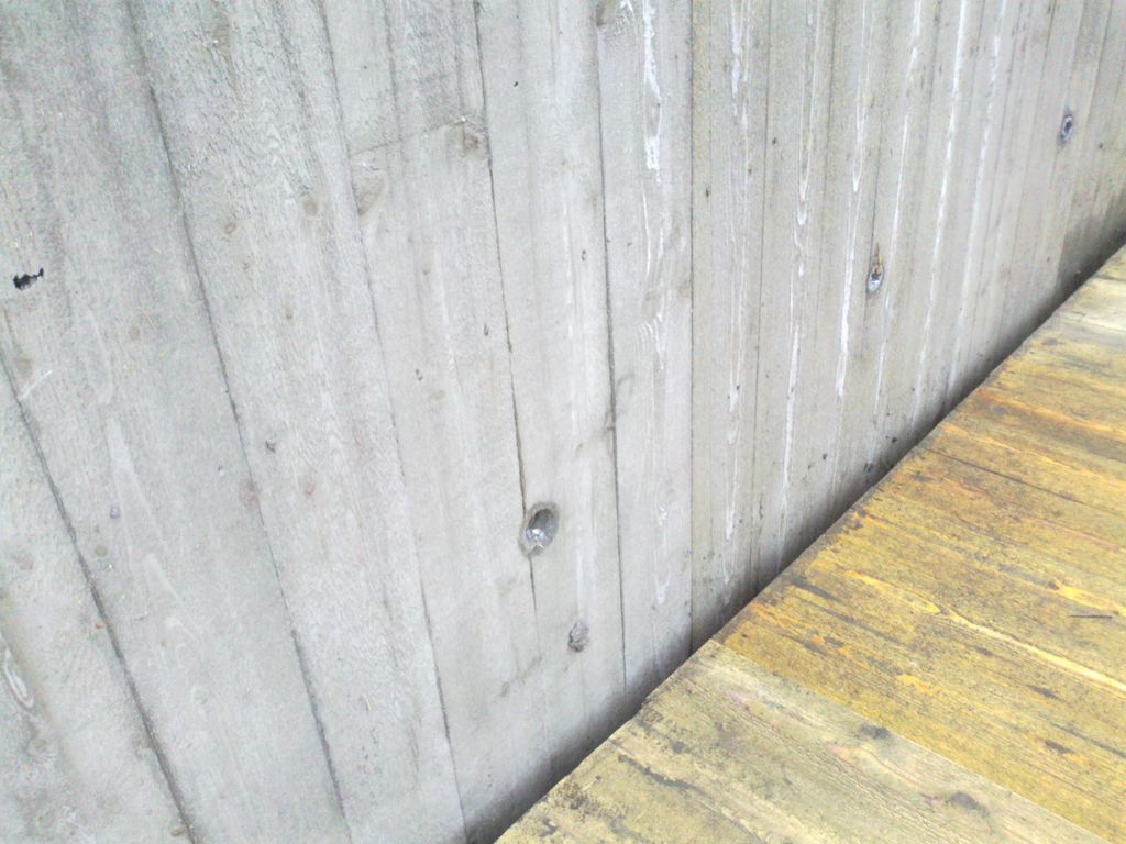 Betongvegg og tregulv. Foto.