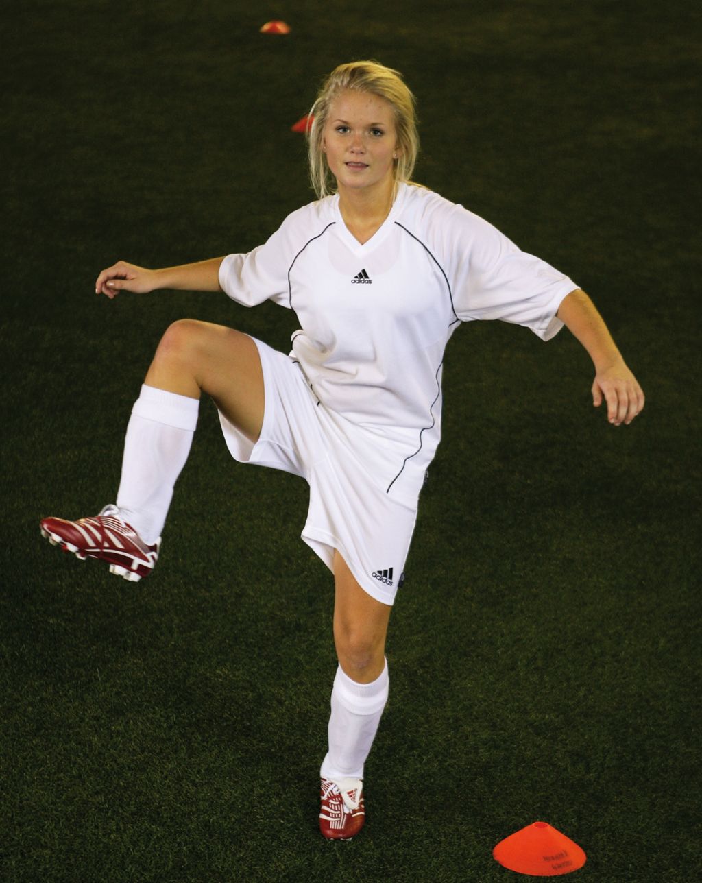 Ei jente varmar opp på ein fotballbane. Foto.