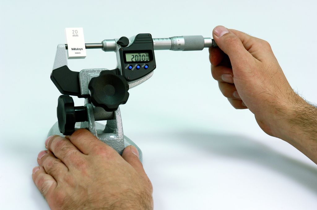 Hender holder digitalt mikrometer og passbit vi bruker til kalibrering. Foto.