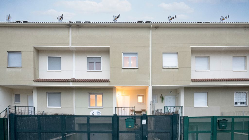 Inngangspartiene til tre rekkehus i mur. Det er lys i den midterste boligen. Foto.