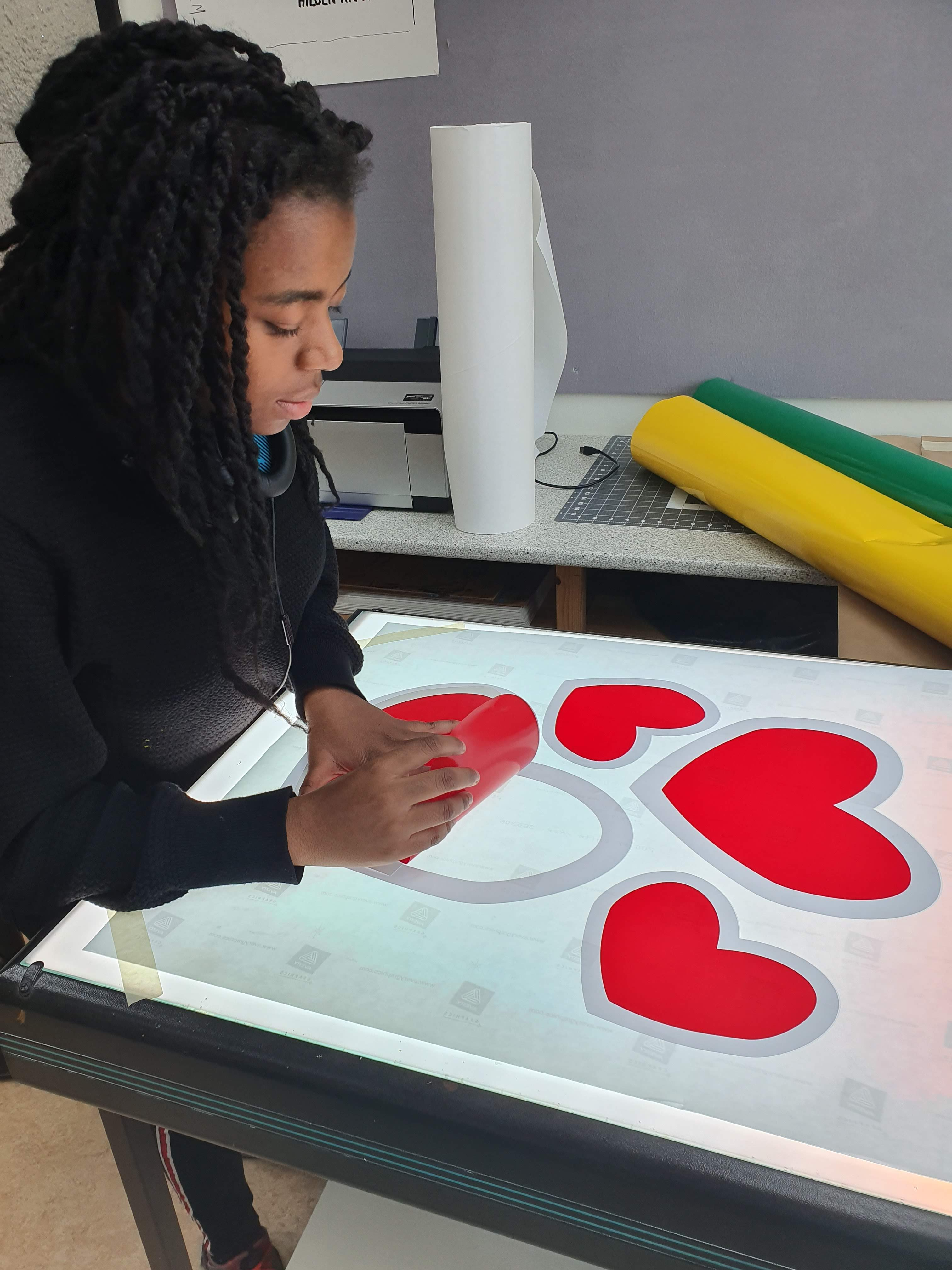 Fotografi av ei jente som lager hjerter i folie.