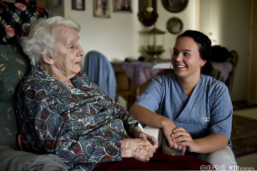 Helsefagarbeider i samtale med kvinnelig beboer på sykehjem. Foto.