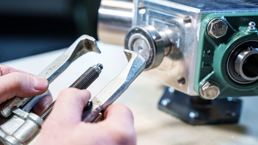 Ei hånd som holder et verktøy med to bein. Foto.