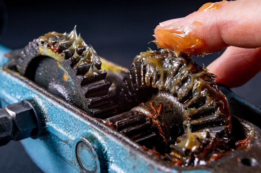 Belegg med fett smøres på en mekanisk enhet. Foto.