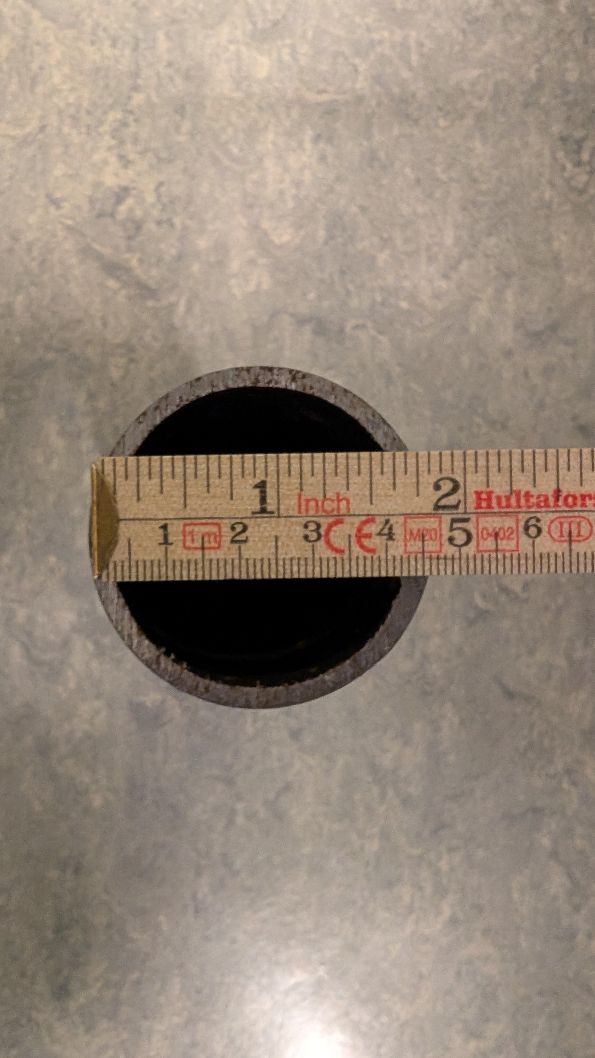 En meterstokk måler den ytre diameteren til et stålrør til å være omtrent 4,6 centimeter. Foto.