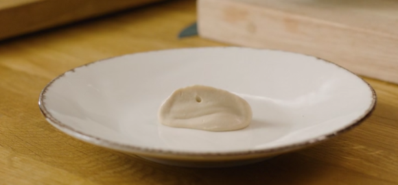 En klatt med blomkålpuré på en hvit tallerken. Foto.