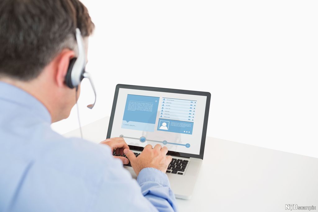 En person som sitter foran en pc. Foto.