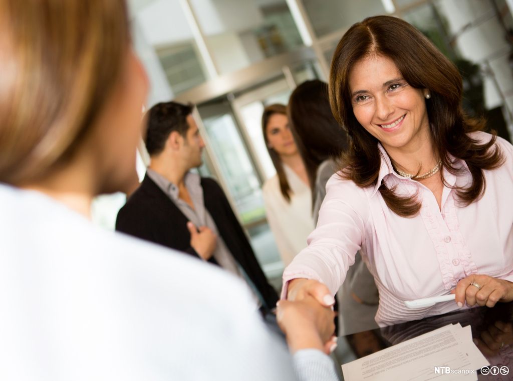 En forretningskvinne sjekker inn på et hotell og smiler. Foto.