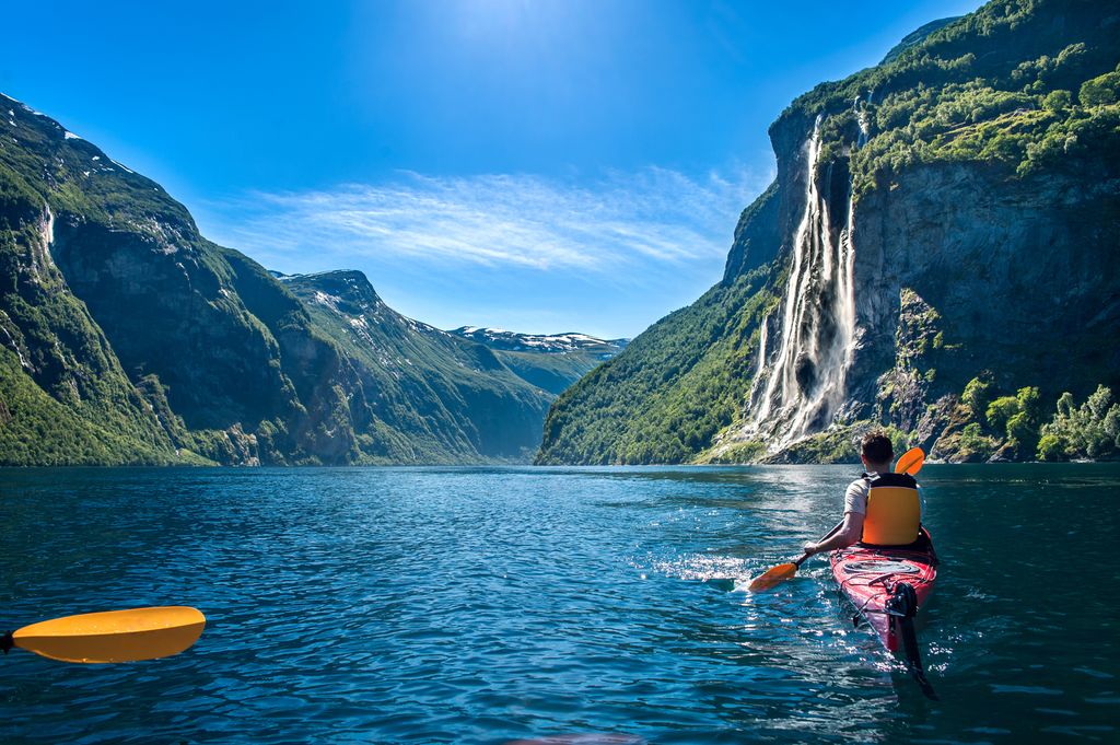 Ung mann i kajakk langs Geirangerfjorden nyter fossen Syv søstre. Foto.