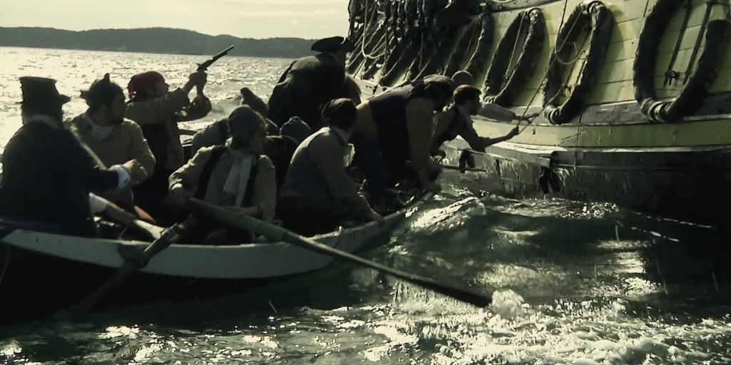 Menn i robåt tek seg om bord på ei seglskute. Foto.