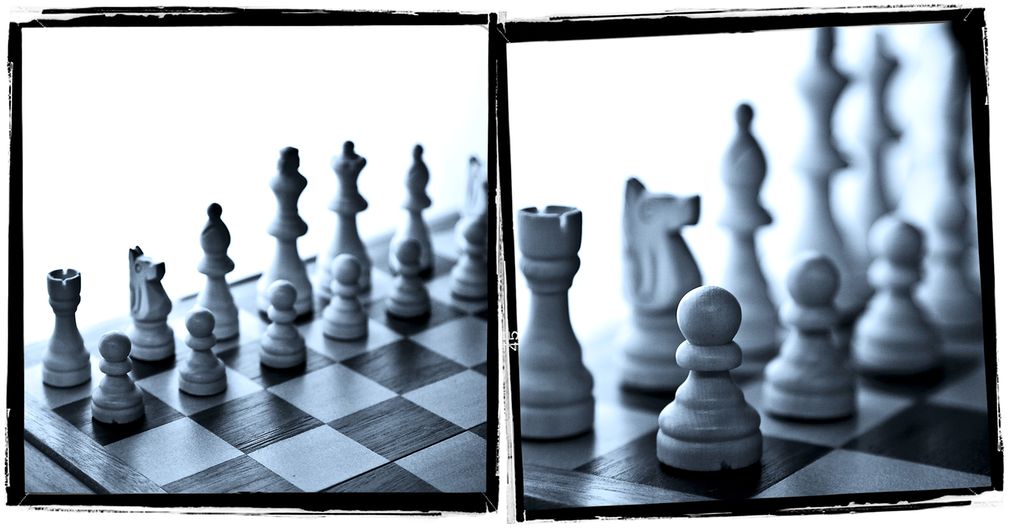 Sjakkbrikker på et sjakkbrett. Brikkene i forgrunnen er skarpe, brikkene i bakgrunnen er uskarpe. Foto.