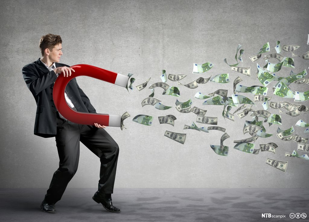 En mann holder en diger magnet som trekker til seg penger. Foto.