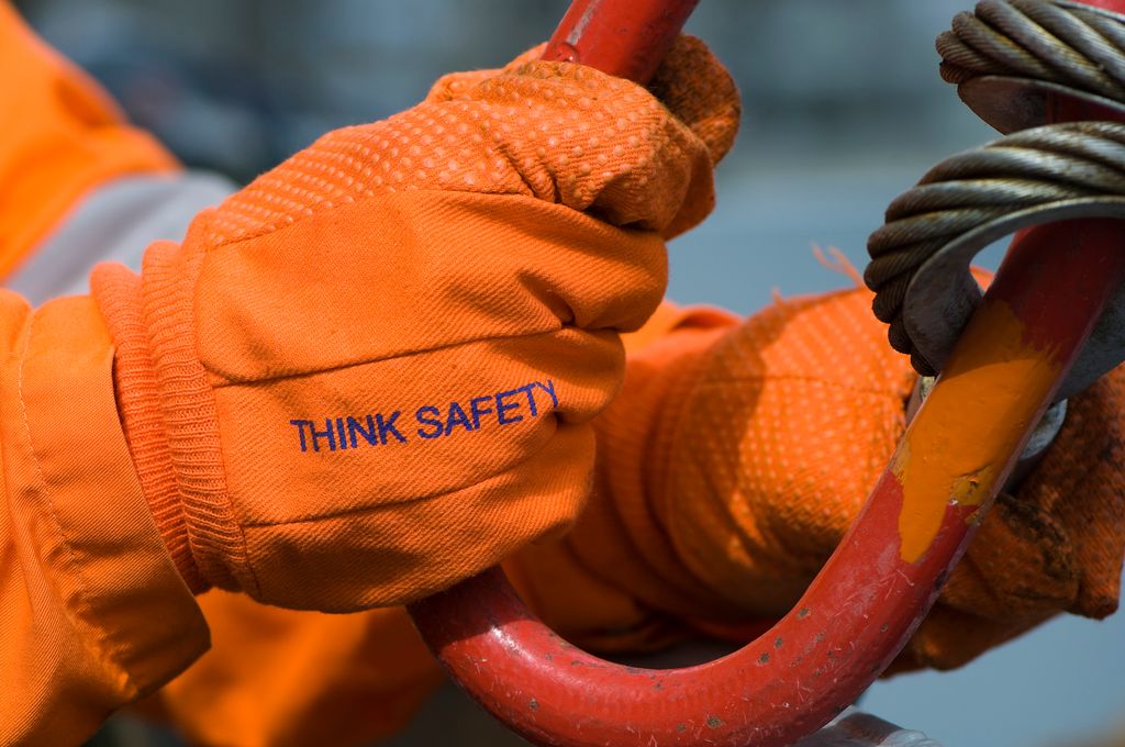 Nærbilde av en oransje hanske med teksten Think Safety. Foto.