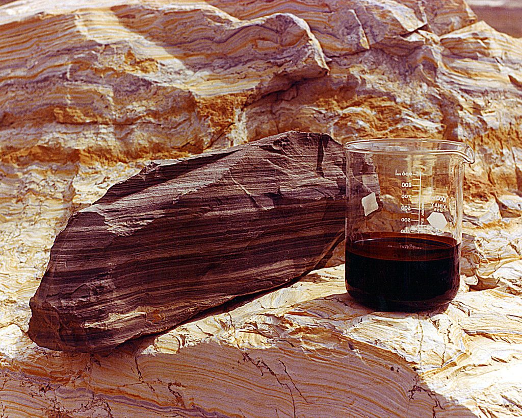Skiferstein og olje i et beger. Foto.
