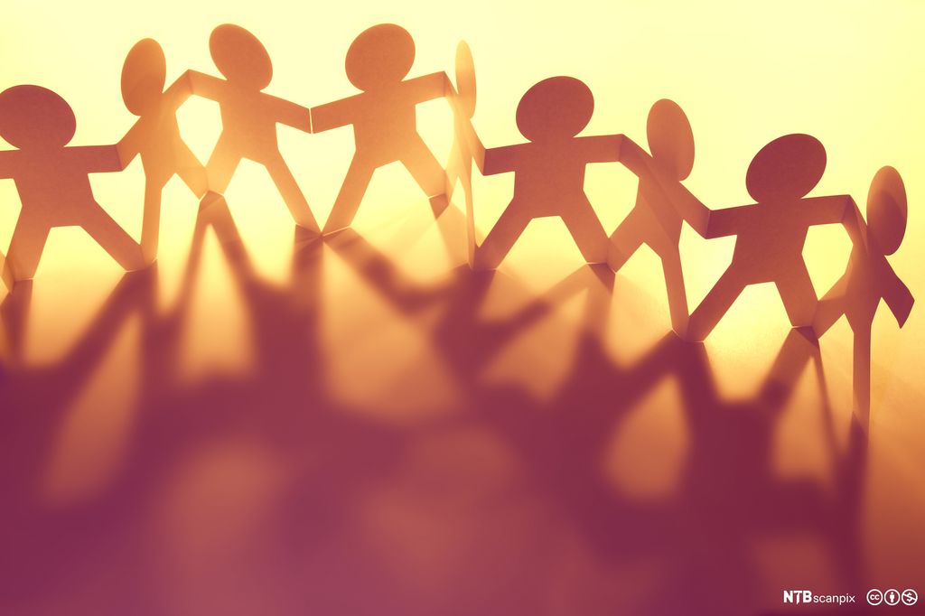 Dolls holding hands cut out of paper. Photo.