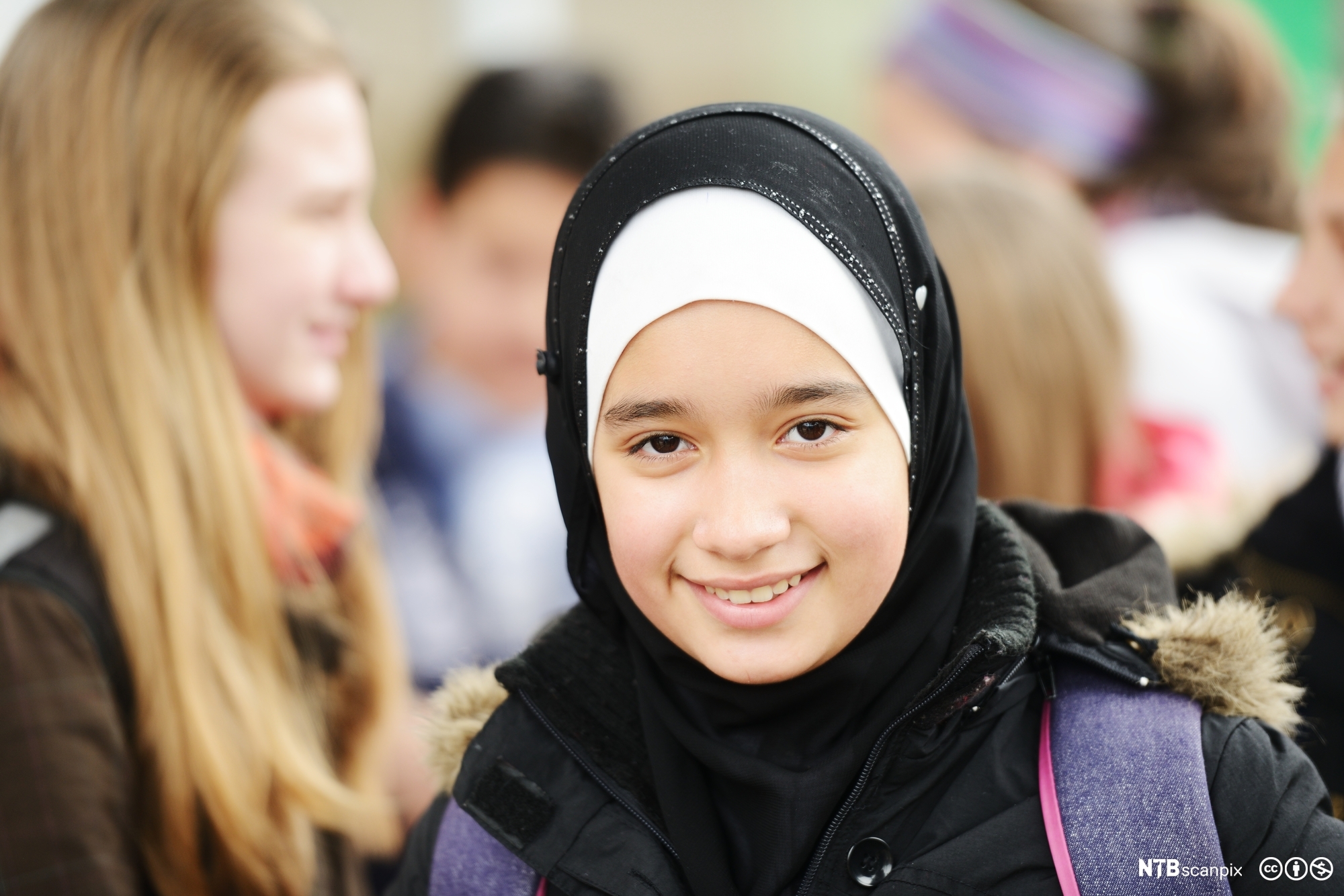 Ung muslimsk elev med hijab blant ikke-muslimer. Foto.