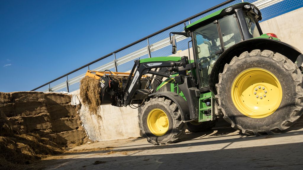 En traktor med frontredskap er i ferd med å ta ut surfôr fra en plansilo. Foto.