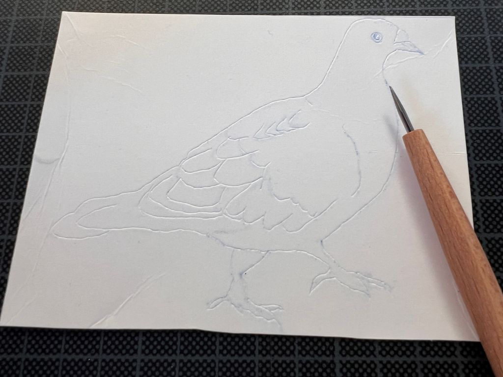 Ei plate med duemotiv og ei rissenål. Foto.