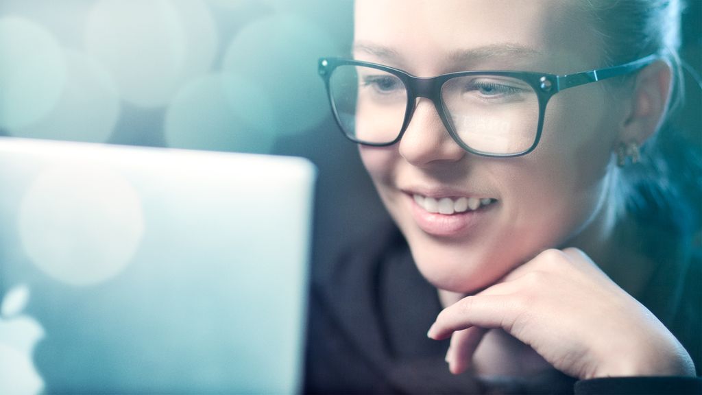 Jente med briller kikker på en dataskjerm. Foto.