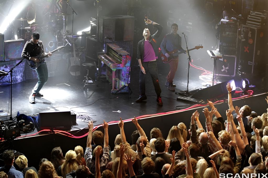 Bandet spiller på scenen, mange i publikum har armene i været. Foto.