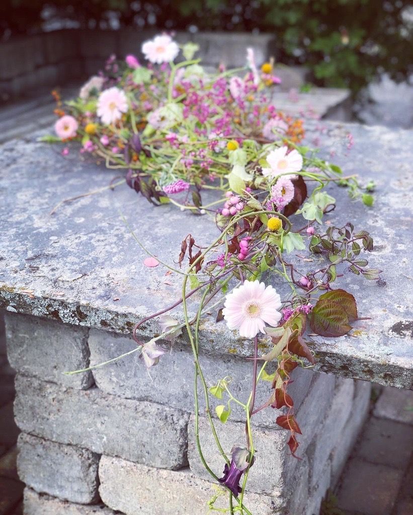 Konstruksjon av greiner i dråpeform. Blomster, frøkapsler og greiner festet i konstruksjonen. Foto.