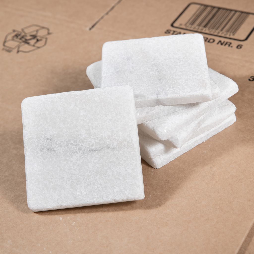 Små, hvite kvadratiske marmorfliser stablet i høyden. Foto. 