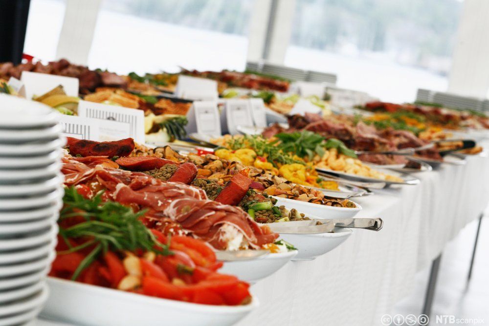 Et koldtbord med mange ulike matretter på store fat. Foto.