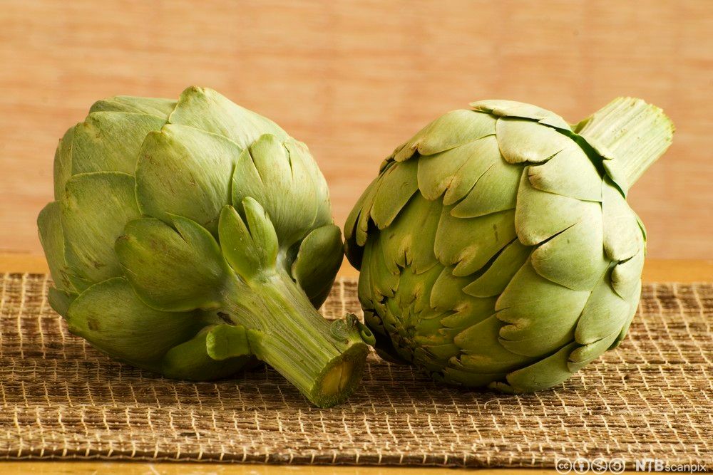To artisjokker på et bord. Foto.
