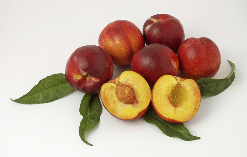 Hele og halve nektarinar på eit bord. Foto.