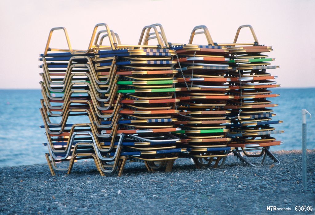 Fotografi av strandsenger i stabel på strand.