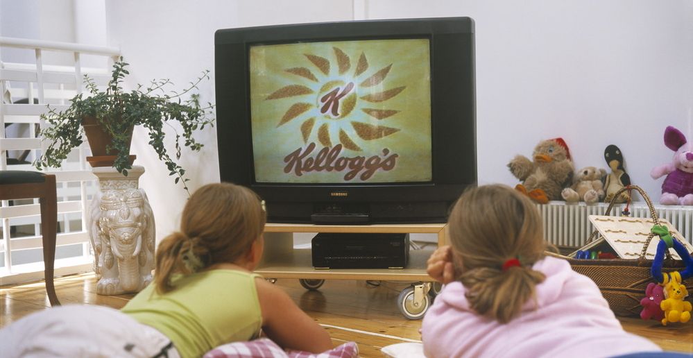 To jenter ligger på gulvet og ser på TV. Foto.