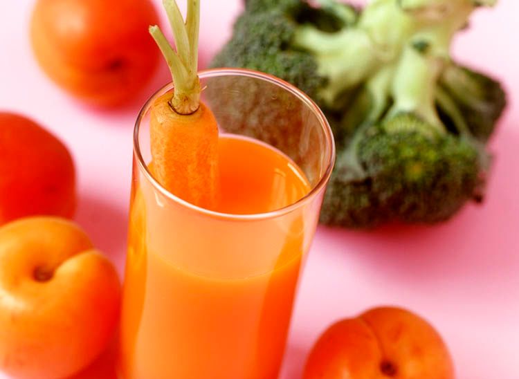 Glass med gulrotjus, brokkoli og frukt. Foto.