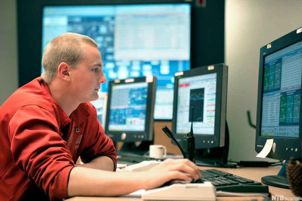  Ung mann sitter foran stasjonær PC. Foto.