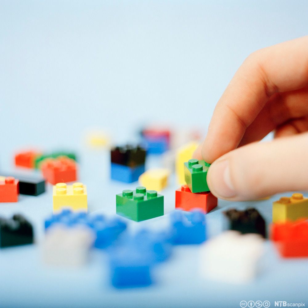 Hand som flytter på byggjeklossar. Foto. 