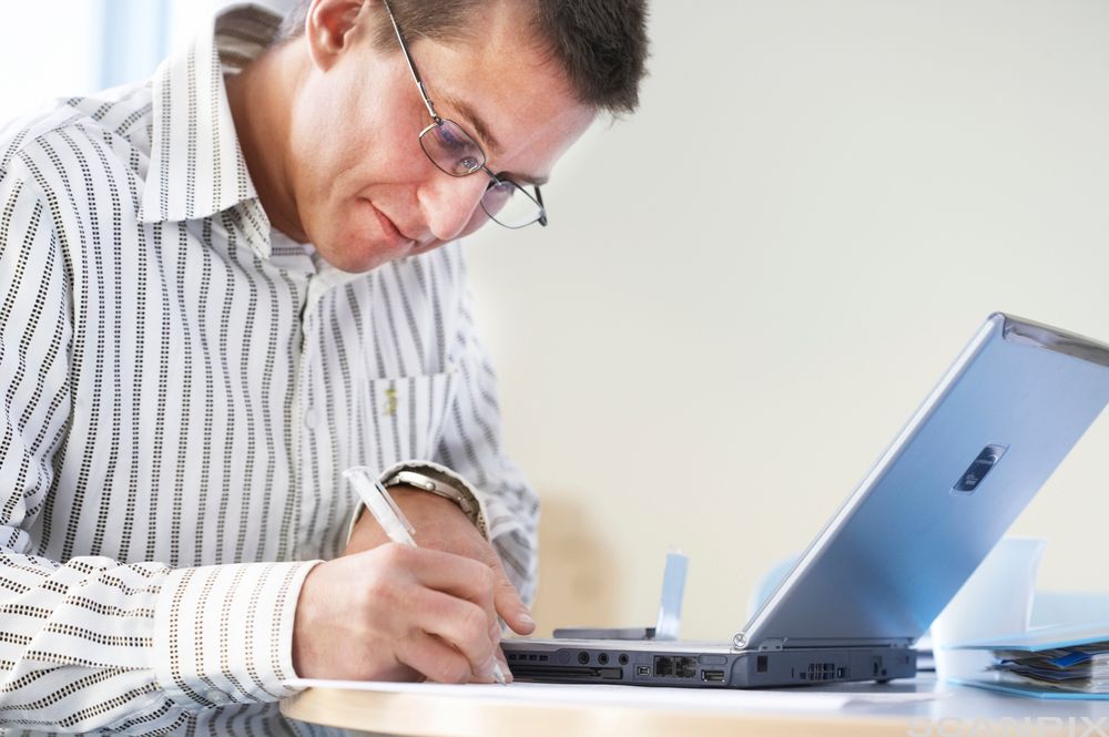 Mann sitter ved en datamaskin og jobber. Foto.