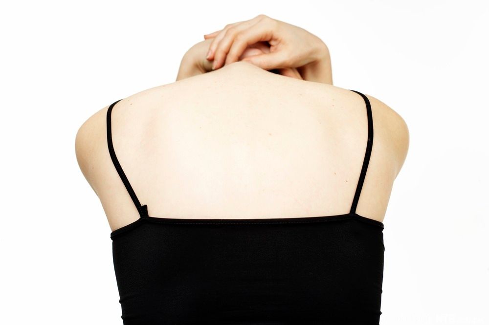 Kvinne med ryggen til bøyer hodet nedover med hendene. Foto.