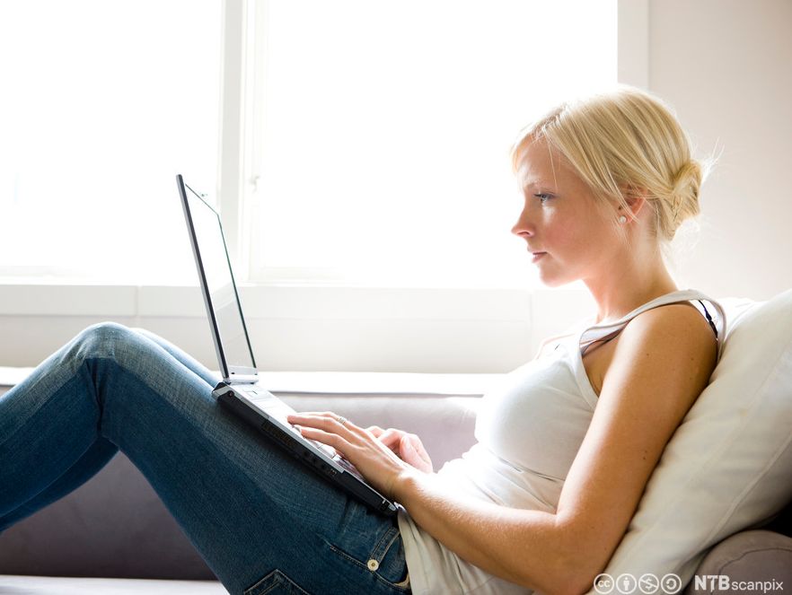 Ung kvinne med berbar datamaskin i fanget. Foto.