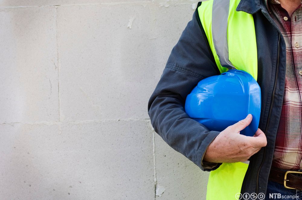 Person med arbeidshjelm under armen. Foto.