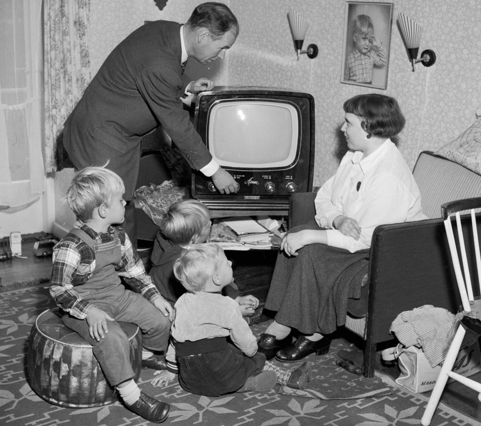 Ein familie er klar til å sjå på fjernsyn på slutten av 1950-talet. Foto.