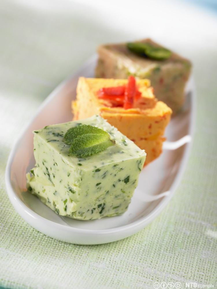 Ulike typer med kryddersmør i terninger på et fat. Foto.