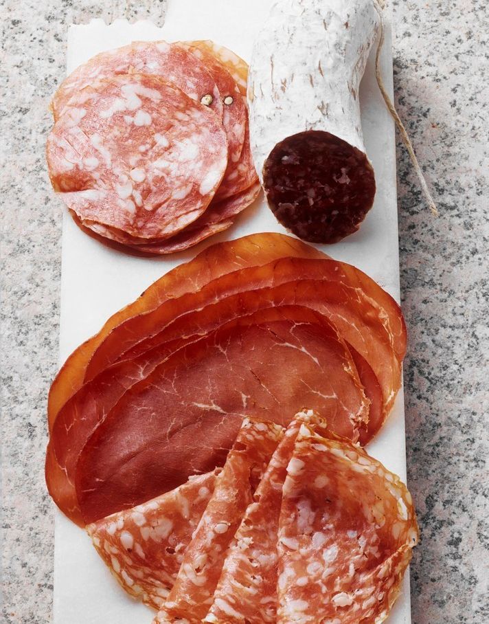 Fjøl med oppskoren spekemat som pølser og skinke. Foto.