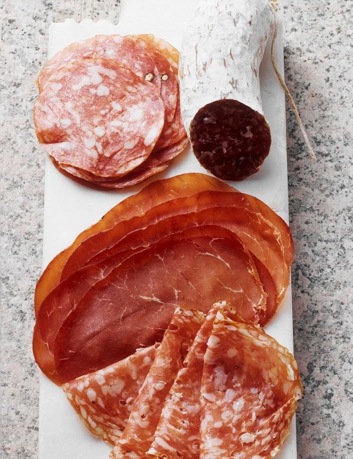 Fjøl med oppskåret spekemat som pølser og skinke. Foto.