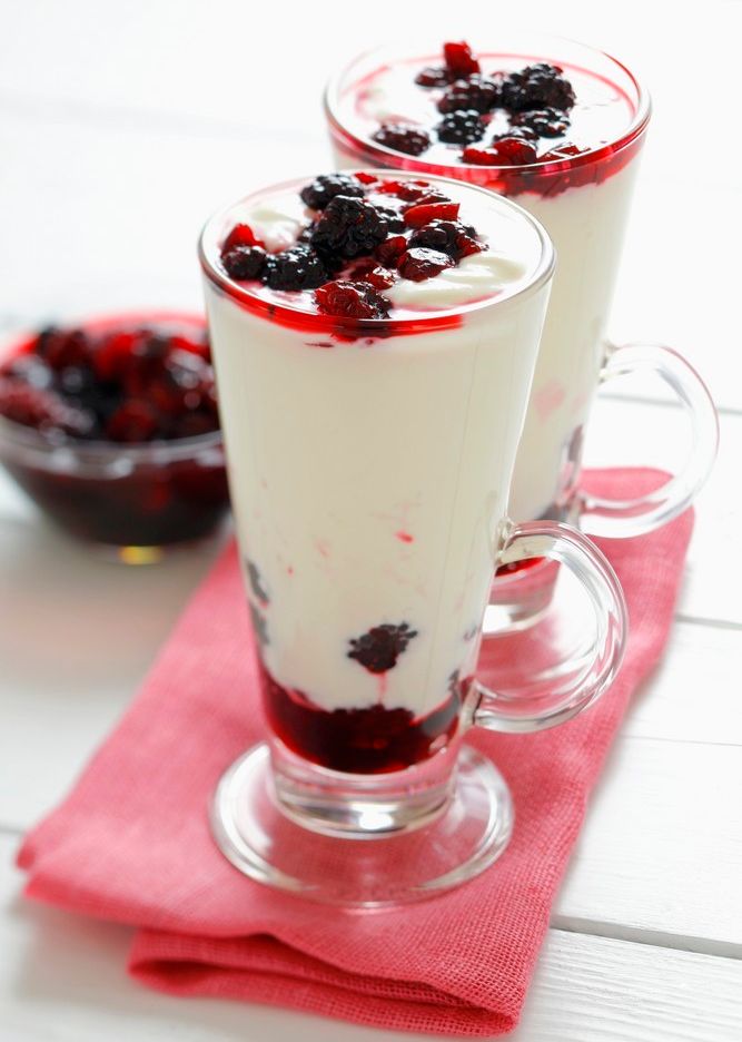 Youghurtdessert med bær i botnen og på toppen servert i høge glas. Foto.