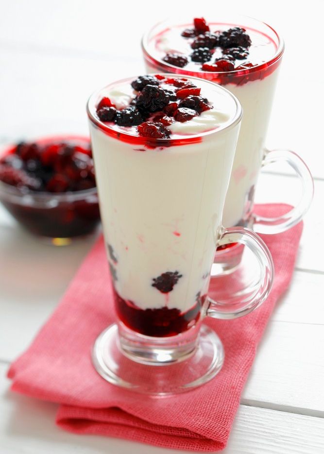 Youghurtdessert med bær i bunnen og på toppen servert i høye glass. Foto.