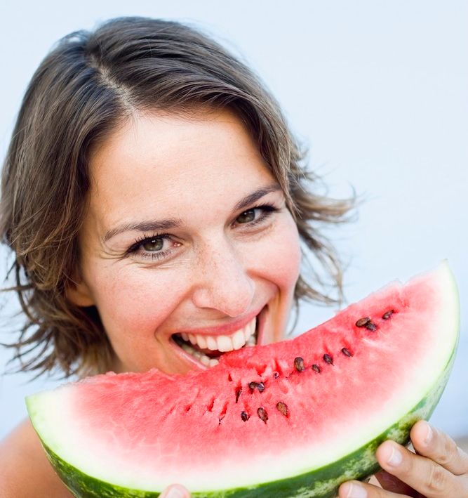 Smilende dame spiser vannmelon. Foto.