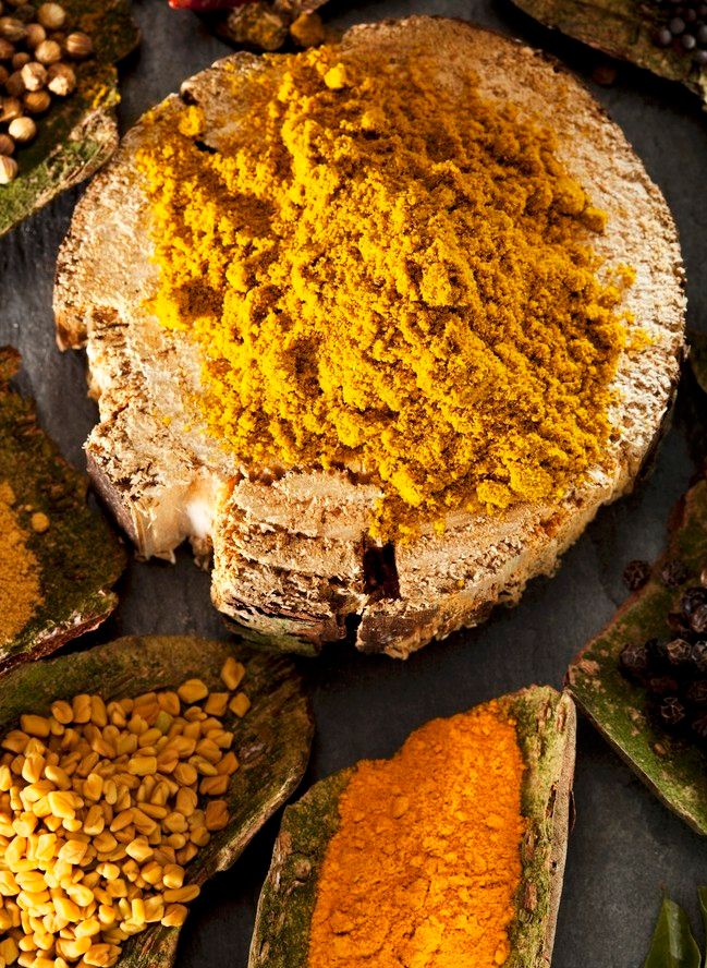 Ein bolle med karrikrydder, og andre småbollar med ulike krydder rundt. Foto.