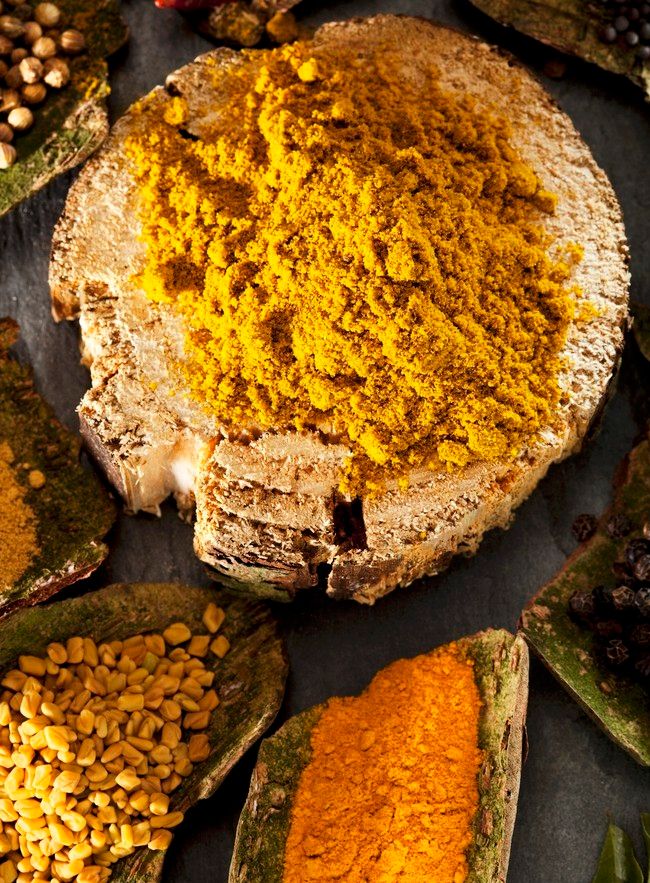 En bolle med karrikrydder, og andre småboller med ulike krydder rundt. Foto.