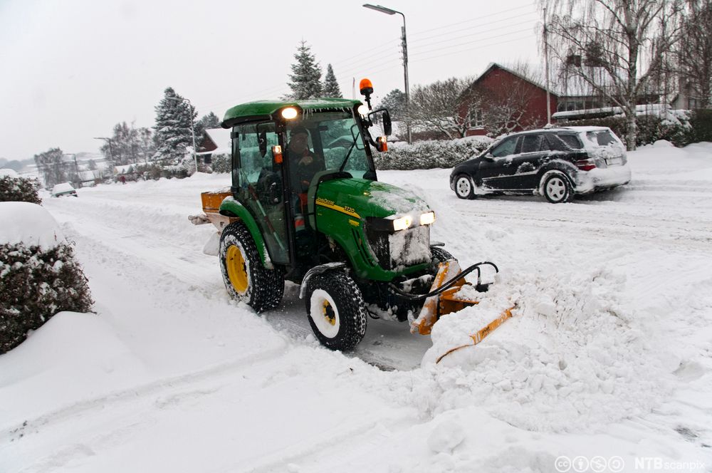Traktor ryddar snø. Foto.
